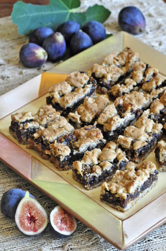 Fig bars on a cutting board with some figs next to the board