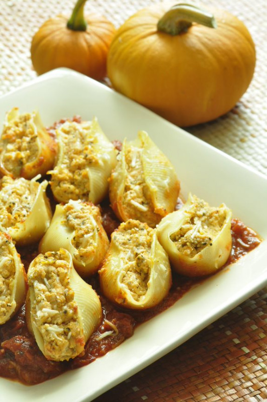Pasta shells stuffed with pumpkin and ricotta cheese with a couple of pumpkins in the background