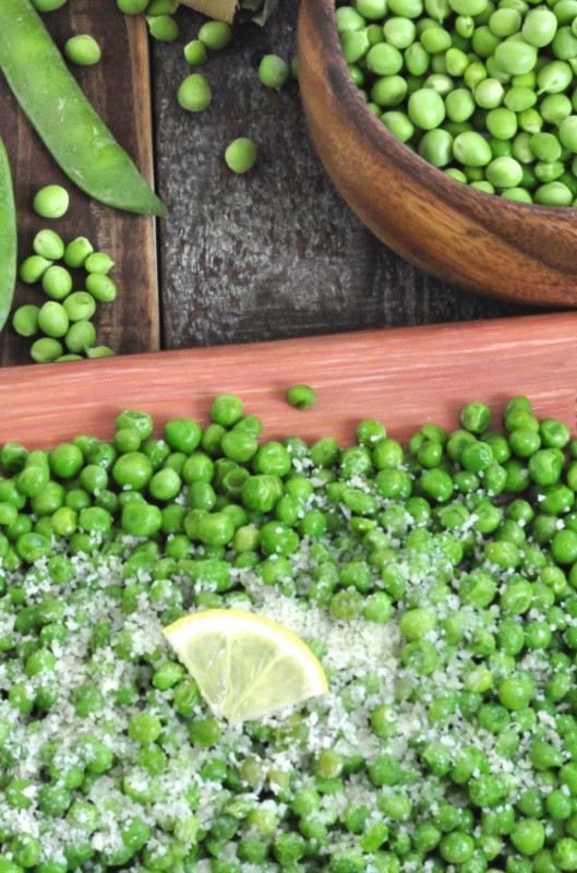 peas in a bowl with parmesan cheese and a lemon wedge
