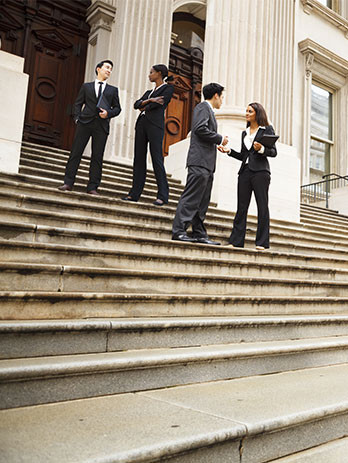group of professional men and women in suits standing outside courthouse steps