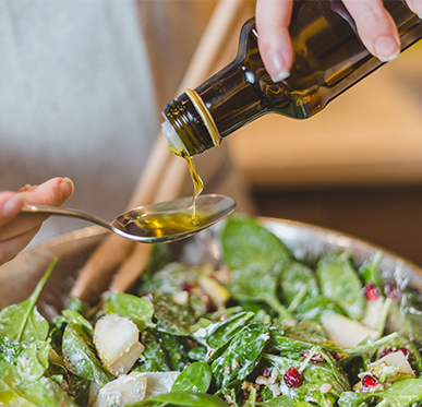 pouring oil on a spoon over a salad