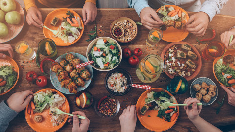 Overhead shot of plates on a tablet and people eating