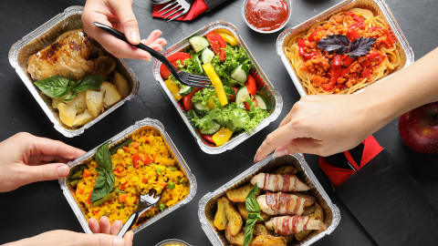 image of an overhead closeup of hands spooning out food from take out containers