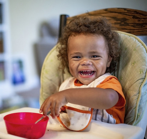 little black baby, laughing in hichair