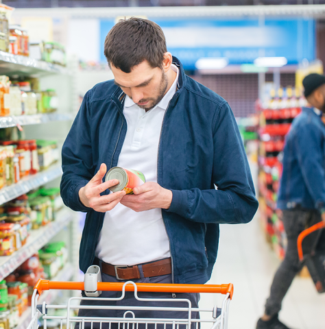 image of a man looking at a canned food label while in the grocery store