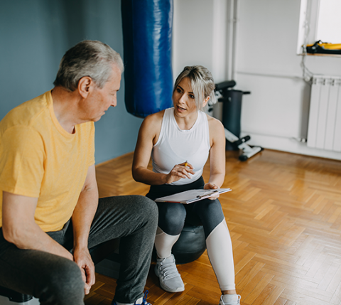 woman trainer sitting with older male client