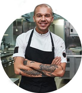 young male chef with tattoos crossing his arms and smiling