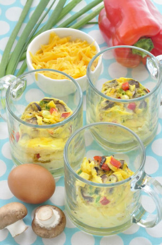 Omelets in a glass mug surrounded by mushrooms and onions
