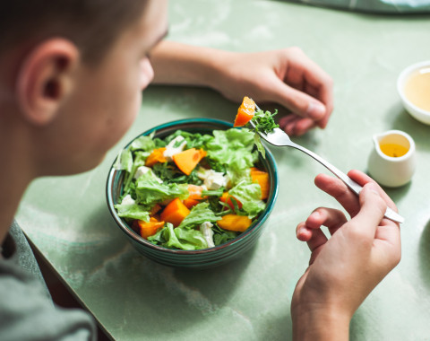 image of teenage boy eating his salad