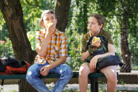 image of teenagers with backpacks eating apples