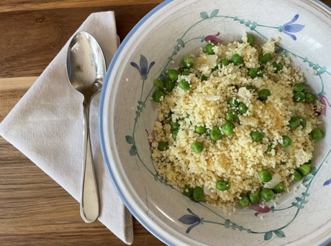 Couscous and peas in a bowl with a spoon on the side