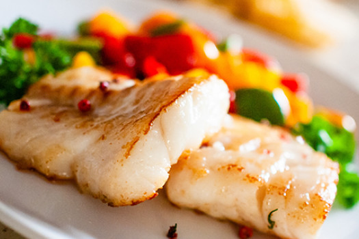 Baked Fish with tomatoes, peppers, and onions on a plate