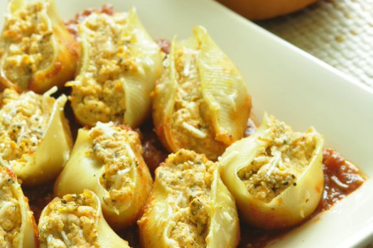 Pasta shells stuffed with pumpkin and ricotta cheese with a couple of pumpkins in the background