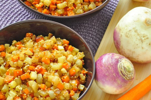 Bowl of sesame turnips and carrots with raw turnips on a cutting board