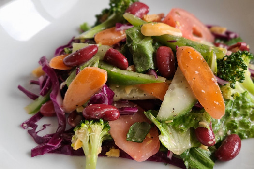 salad with beans, carrots, lettuce, cucumbers, and broccoli on a plate