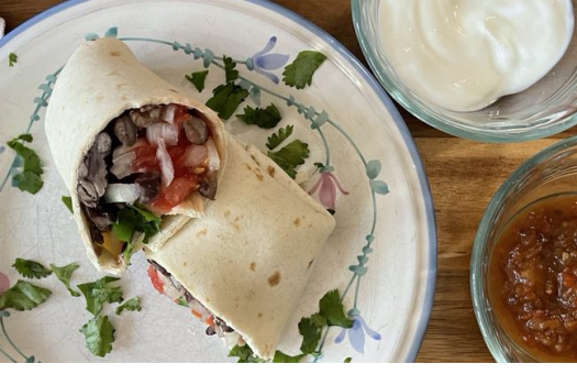 bean burrito on a plate with a side of yogurt and salsa