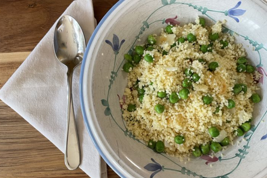 Couscous and peas in a bowl with a spoon on the side