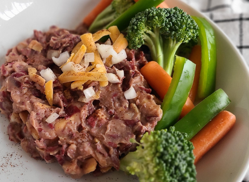 Bean dip on a plate with broccoli and carrots on the side